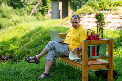 Young man using laptop while sitting on field