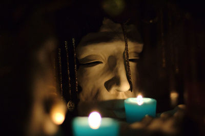 Illuminated candles against statue