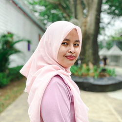 Portrait of hijab muslim young woman standing against trees