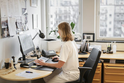 Side view of woman sitting on table