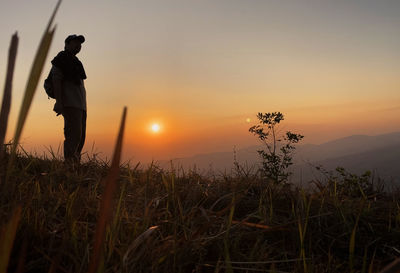 Silhouette man standing on field against sky during sunset