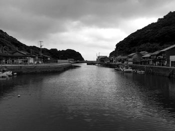 Canal amidst houses in town against cloudy sky