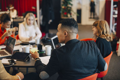 Businessman discussing with colleagues while sitting at conference table during meeting in office