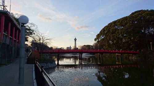 Bridge over river by buildings in city against sky