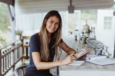 Portrait of smiling female owner using digital tablet while in restaurant