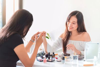 Beautician applying nail polish on woman hands over table