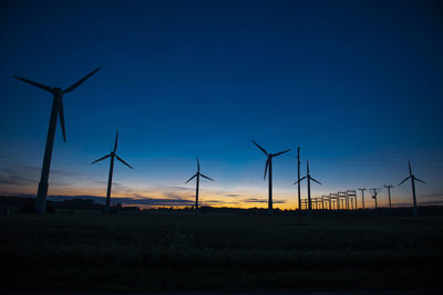 Power generators of windmills at shadow sunset - wind turbine on field at sunset