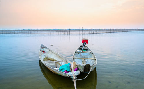 Boat moored in lake against sky during sunset