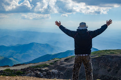 Rear view of man standing on mountain against sky