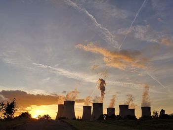 Smoke stacks against sky during sunset