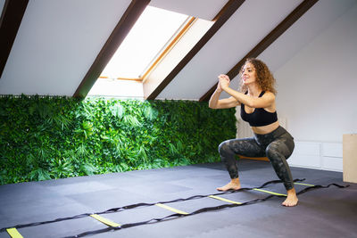 Full length of young woman exercising in gym