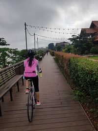 Rear view of woman riding bicycle on bridge