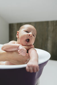 Cropped hands of mother bathing son in bathtub at bathroom