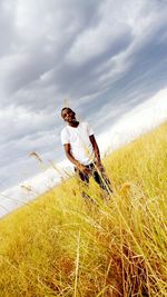 Tilt image of young man standing on grassy landscape