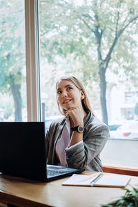 Young woman using mobile phone while sitting on table