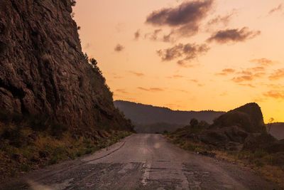 Road by mountain against sky during sunset