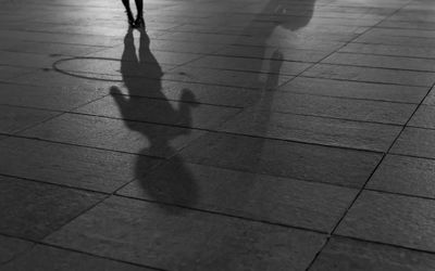 Low section of woman walking on footpath at night