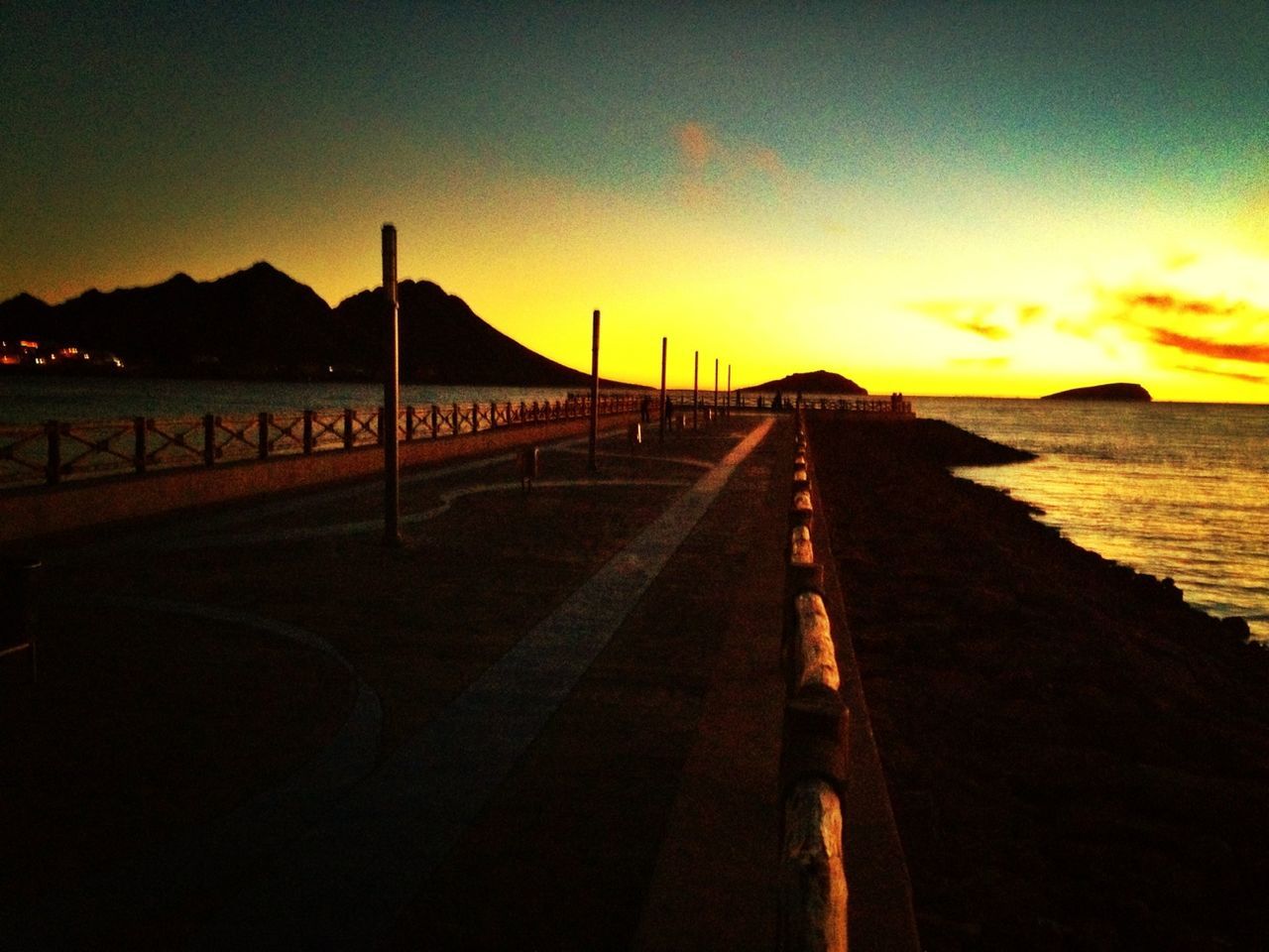 sunset, the way forward, sky, sea, water, silhouette, tranquil scene, orange color, scenics, tranquility, beauty in nature, diminishing perspective, transportation, beach, dusk, nature, vanishing point, mountain, idyllic, pier