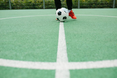 Low section of person playing soccer ball on grass