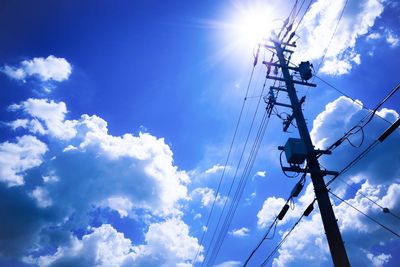 Low angle view of electricity pylon against blue sky