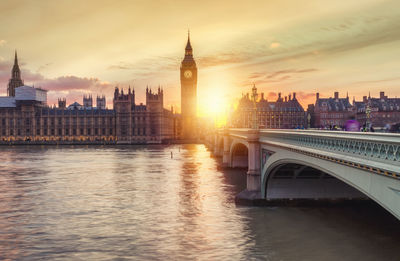 Big ben by thames river during sunset