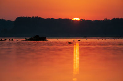 Scenic view of lake against orange sky