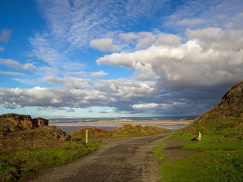 Dirt road along landscape against sky