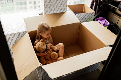 Cute girl with toy sitting in box