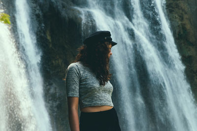 Rear view of woman standing against waterfall