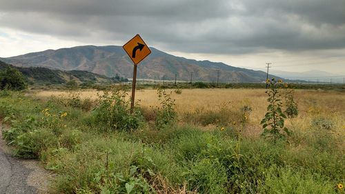 Road sign on grassy field against mountains