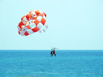 Man with umbrella on sea against clear sky