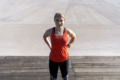 Female jogger standing on pier during sunny day