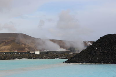 Smoke emitting from lake against sky