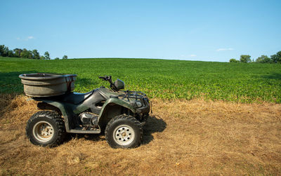 Soybean field extends up the hillside to the horizon with an off road vehicle in foreground.