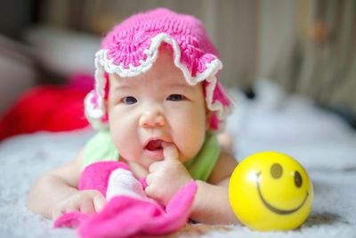 Portrait of cute baby girl with toy on bed