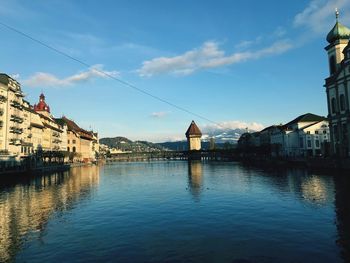 Buildings by river against sky in city