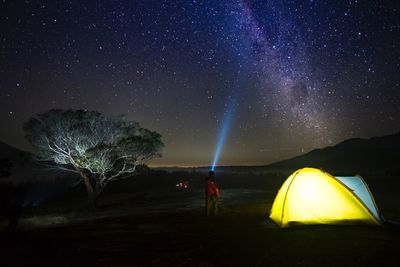 People standing on illuminated star field against sky at night