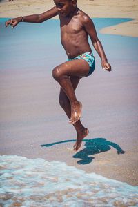 Full length of boy enjoying on shore at beach