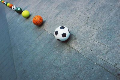 Balls of various sports line on sidewalk