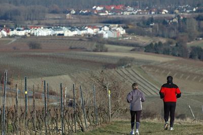 Rear view of people jogging on field