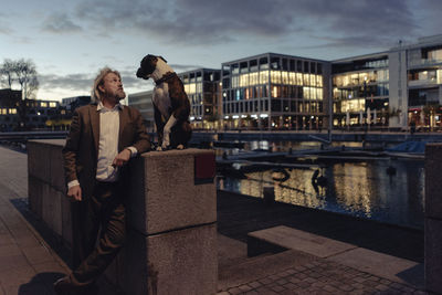 Senior man standing with dog at the lakeside in the evening