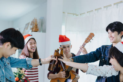 Friends toasting beer bottles during celebration at home