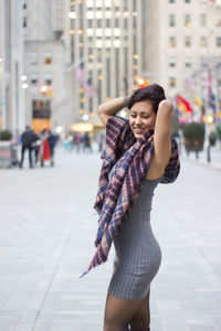 Young woman wearing mini dress with shawl standing on city street