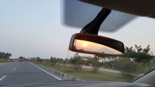 Close-up of wet car on road against sky