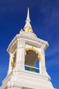 Low angle view of carvings on bell tower at temple against blue sky
