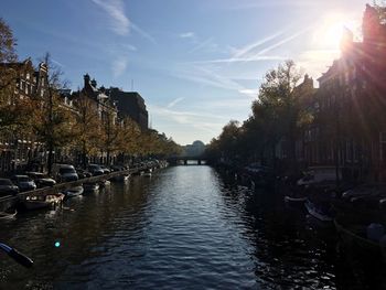 Canal amidst trees against sky in city