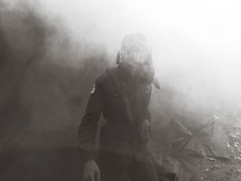 Person wearing gas mask standing amid smoke