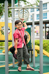 Young asian children hang on the monkey bar. to exercise at outdoor playground in the neighbourhood.