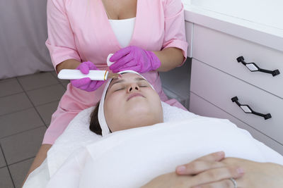 Facial cleansing with ultrasound scrubber, pore cleaning machine. young woman receiving ultrasound