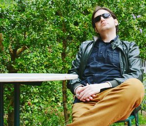 Mature man sitting on chair against trees in forest